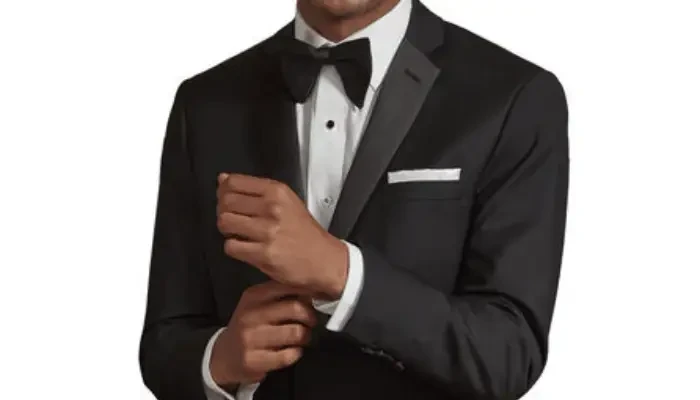 Groom in a black tuxedo adjusting his cuff or sleeve.