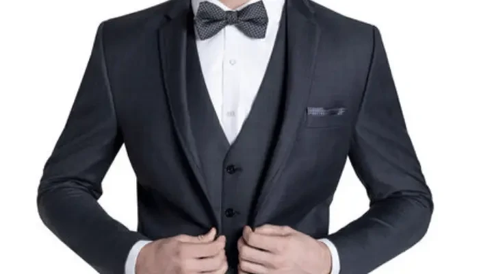 Groom wearing a dark navy tuxedo with a vest and patterned bow tie.