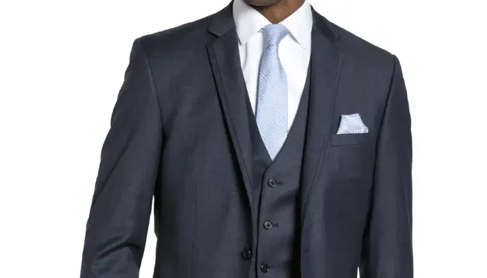 Close-up of a man wearing a dark gray three-piece suit with a light blue tie and matching pocket square.