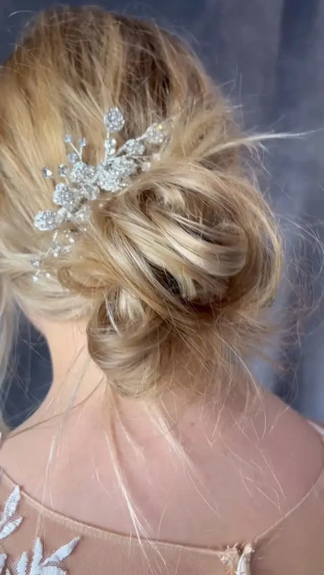 Elegant bridal updo with a crystal hairpiece accentuating the twisted bun hairstyle.